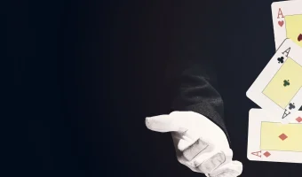 Mâinile unui magician demonstrând un truc cu cărți de joc pe fundal negru