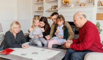 Bunici, părinți și copii jucând cărți împreună în sufragerie